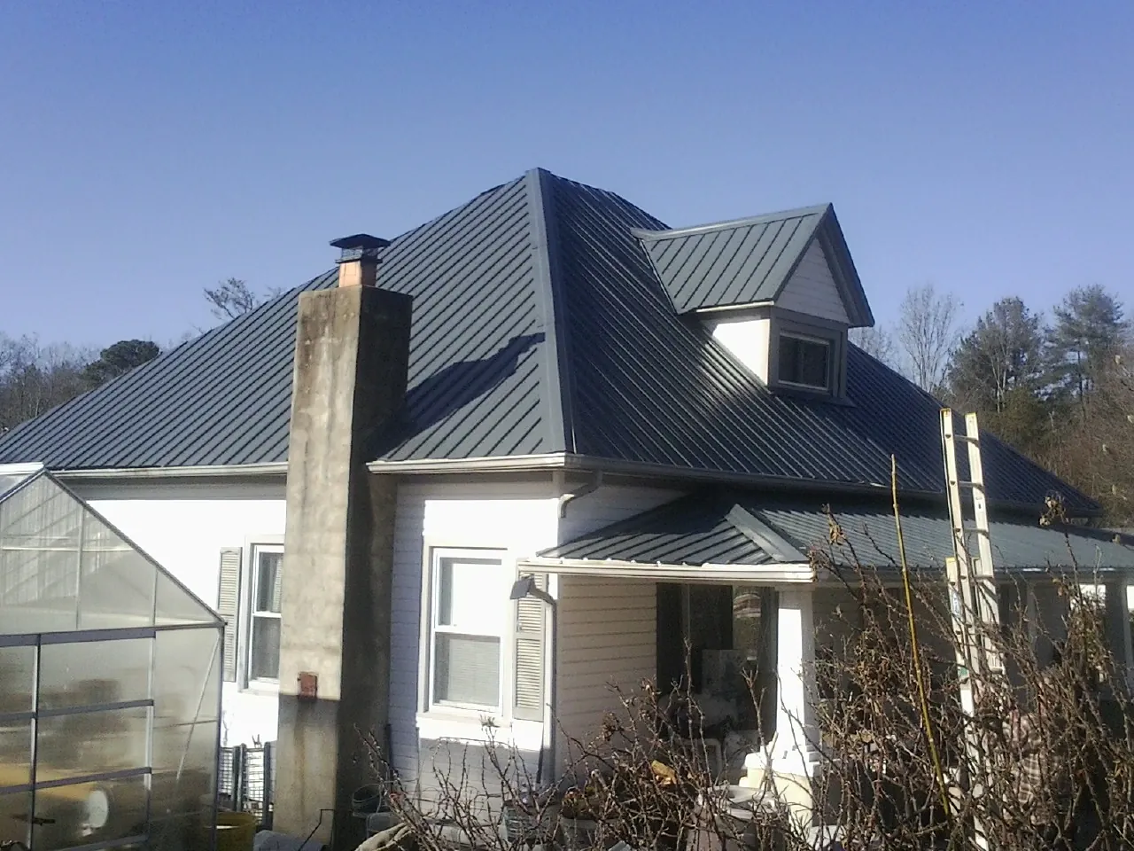 Dark blue standing seam metal roof on a white farmhouse with dormer — Slate & Tile Roof Repair by Roofing Brothers in Itasca