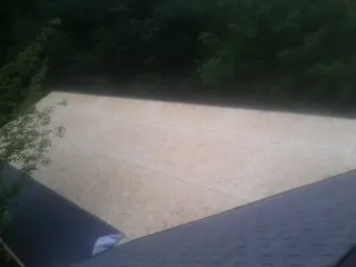 New OSB roof sheathing installed beside an existing shingle roof in Itasca