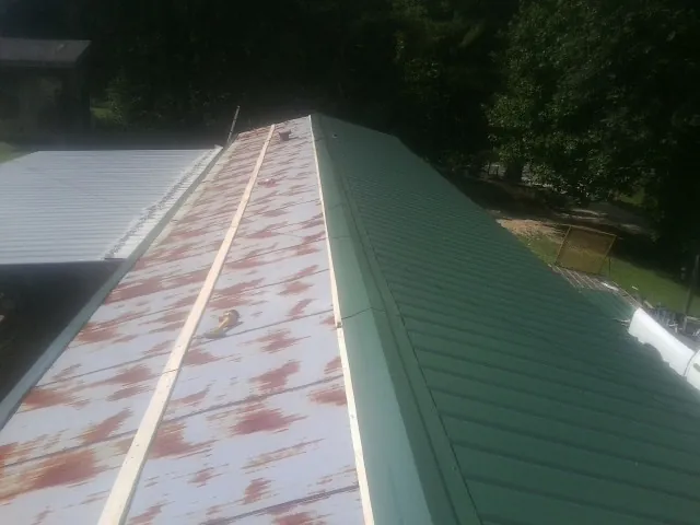 Old rusted panels beside newly installed green metal roofing — Wind Damage Roof Repair by Roofing Brothers in Itasca