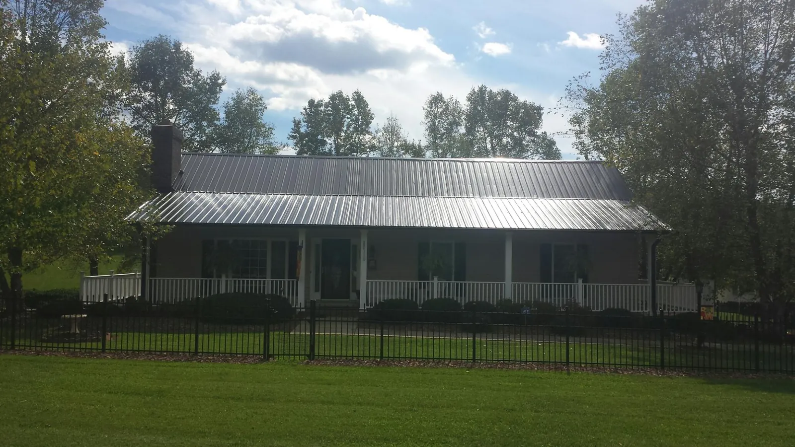 Gray metal roof on a brick ranch with a full width front porch — Gutter Guard Installation work by our crew in Itasca