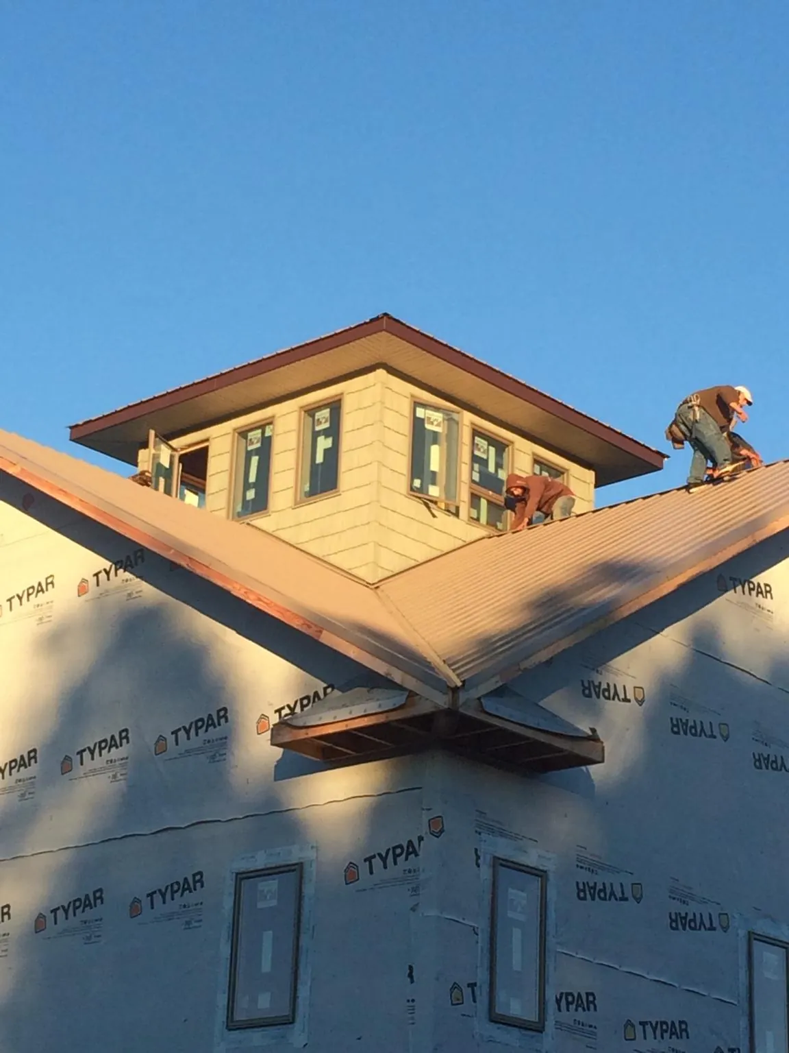 Roofers working around a rooftop cupola on a new metal roof at sunset — Roof Waterproofing in Itasca by Roofing Brothers